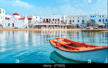 Beautiful summer day, Greek island seafront. Fishing boats, whitewashed houses. Red dome church. Small boat in foreground. Mykonos, Cyclades, Greece. Stock Photo