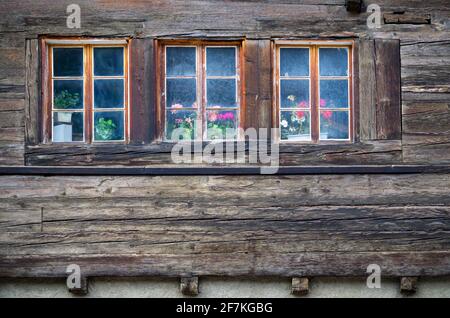 Old rustic windows with flowerpots on an rustic wooden alpine house, Oberwald, Switzerland. Stock Photo