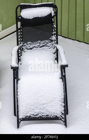 Modern sunlounger or folding chair outdoors covered in fresh snow Stock Photo