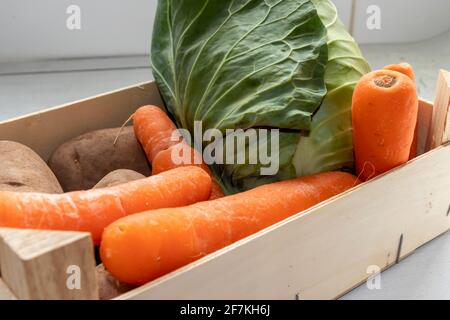 Selection of Fresh Vegetables displayed in a small Wooden Crate Stock Photo