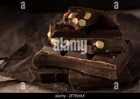 Dark chocolate with almonds and hazelnuts in a stack on brown background Stock Photo