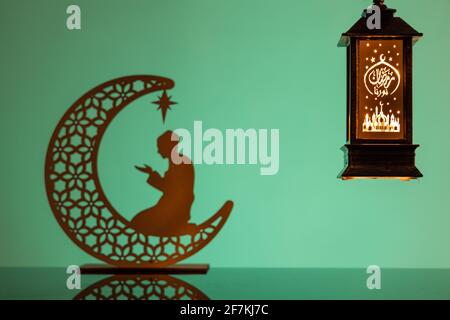 Eid Mubarak concepts with lamp inscribed with arabic text translated to english as Ramadhan is our light., with crescent moon in silhouette Stock Photo