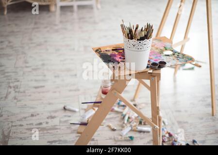 Artist paintbrushes, paint tubes and small easel with canvas