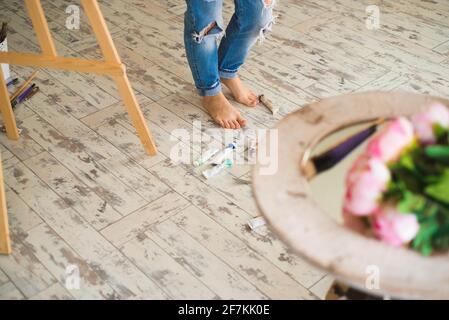 Young inspired girl choosing paint tube in light studio. Stock Photo