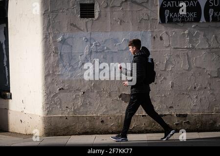 A young man walking past a run down pub in Preston City centre with a cigarette in his mouth. Stock Photo