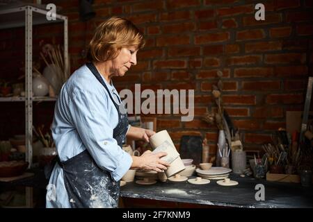 Charming elderly woman working in pottery studio Stock Photo