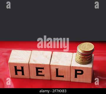 HELP the word on wooden cubes, cubes stand on a reflective red surface and stack of coins. Business social concept. Stock Photo