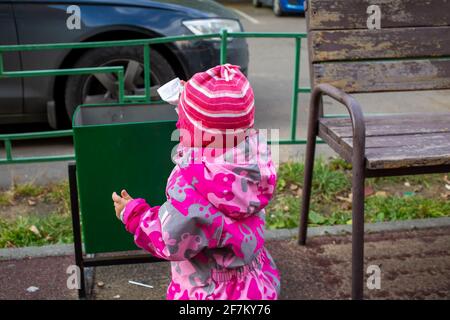 adorable toddler throws trash in a street bin Stock Photo