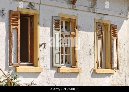 Old damaged windows with shutters of old abandoned building Stock Photo