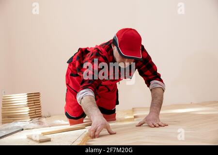 Worker installing parquet floor during home renovation, Construction in a renovated room installation of parquet Stock Photo