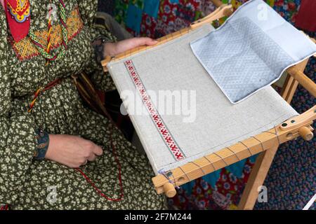 Woman makes cloth on an old loom. Festival of historical reconstruction. Clothing weaving process. Stock Photo