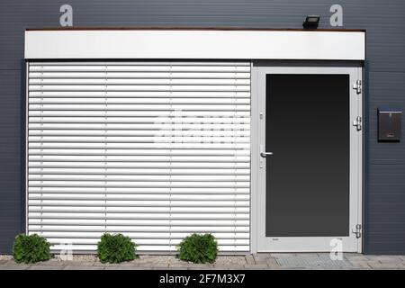 Metal blinds on the windows and doors of the gray facade of the shop. Stock Photo