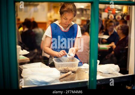 Asian woman making dumplings in Chinese (canteen style) restaurant. Chinatown, London, UK. Aug 2015 Stock Photo