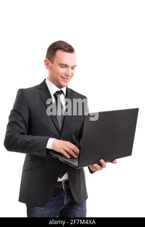 Portrait of a young attractive businessman in a suit jacket holding a laptop in hands reading, writing something and smiling, isolated on white. Stock Photo