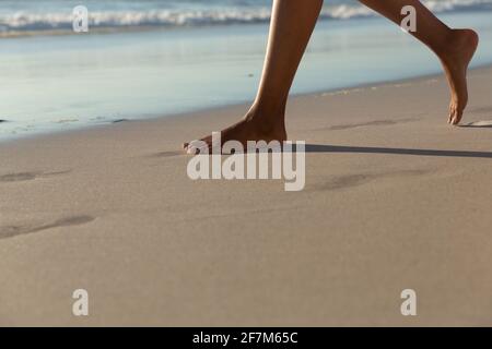 Low section of mixed race woman on beach practicing yoga durning sunset Stock Photo