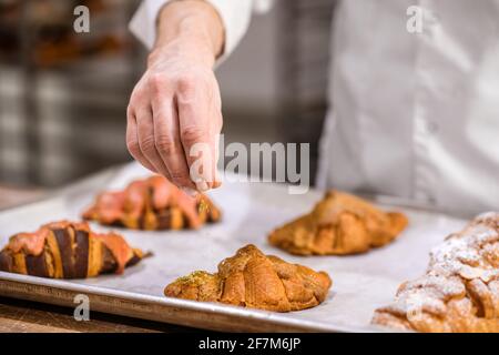 Confectioner hand decorating surface of cooked pastries Stock Photo