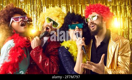 Group of happy people in funny wigs and costumes singing and