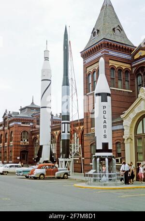 ‘Rocket Row’ along the west side of the Arts and Industries Building (before the National Air and Space Museum was built), Washington DC, USA in 1964. The four missiles are the Jupiter C, which launched Explorer I, the first U.S. satellite (left), the Vanguard (centre) and the Polaris A-1, the first U.S. submarine-launched ICBM (right). Cars are parked in the parking lot. The Air and Space Museum was originally called the National Air Museum when formed in 1946. This image is from an old American amateur Kodak colour transparency – a vintage 1960s photograph. Stock Photo
