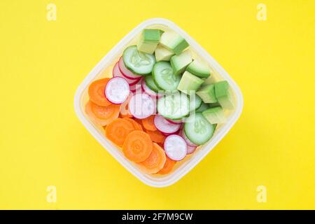 Vegetarian snack or lunch  in the box in the center of  the yellow background. Top view. Closeup. Healthy food ingredients. Stock Photo