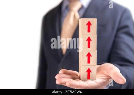 Sales and economic growth concept. Financial growth graph. Sales increase, marketing strategy concept. Businessman hold wooden cubes with red arrow si Stock Photo