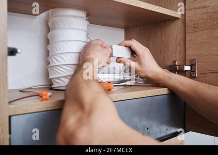 Electrician connect wire in the kitchen cabinet.  Kitchen repair and renovation Stock Photo