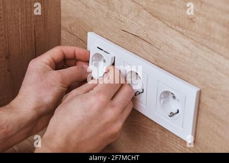 Electrician hands mounting socket in the wall. Socket installation Stock Photo