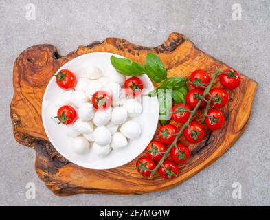 Italian tricolore, small balls of fresh white soft Italian mozzarella cheese, ripe red cherry tomatoes and fresh green basil herb, ready for making ca Stock Photo