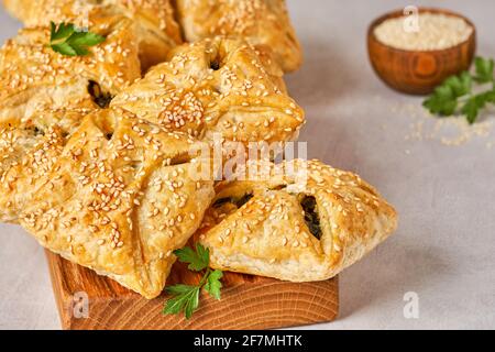 Puff pastry filled with spinach, chicken and cheese on wooden board. Closeup Stock Photo