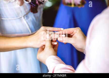 The groom puts the wedding ring on the bride finger.  Stock Photo