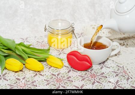 Side view of the pouring of tea, flowers, cookies and honey. Selective focus Stock Photo