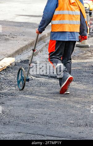 A road service worker measures the jobsite with an electronic measuring wheel. Stock Photo