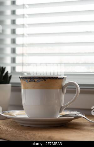 Cup of coffee, spoon and saucer on the background of a window on a rainy day Stock Photo