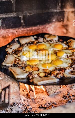 Scrambled egg fried on coals in pan on fire, cook over an open fire. Grilled fried egg Stock Photo