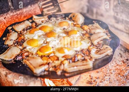 Scrambled egg fried on coals in pan on fire, cook over an open fire. Grilled fried egg Stock Photo