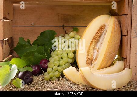 Freshly chopped melon. Yellow melon and fruit in a wooden box. Rustic style. Stock Photo