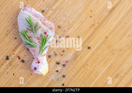 Fresh raw chicken drumstick leg with rosemary, spices and olive oil on kitchen cutting board Stock Photo