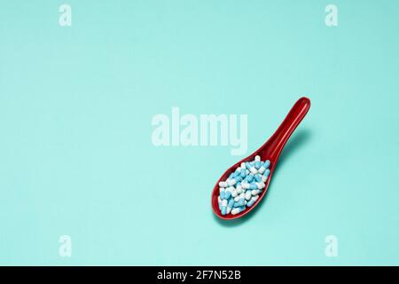 Pharmaceutical medicine pill capsules, in plastic spoon on colorful background. Stock Photo