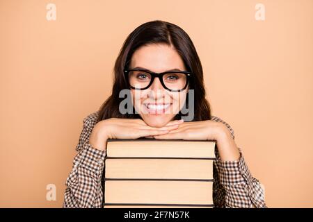 Portrait of attractive cheerful educated wavy-haired girl holding pile book isolated over beige pastel color background Stock Photo