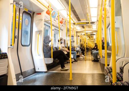 Onboard a London Underground train on the District Line. The train is relatively empty due to coronavirus and all passengers are seated.