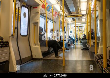 Onboard a London Underground train on the District Line. The train is relatively empty due to coronavirus and all passengers are seated. Stock Photo