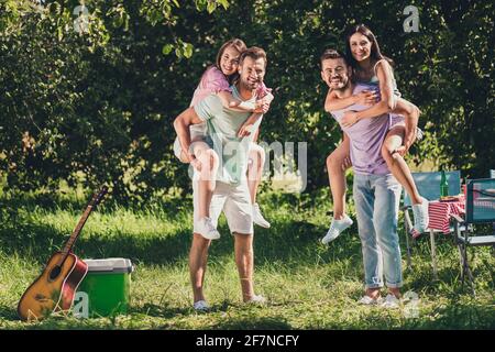 Full length photo of company four members having fun sitting piggyback outside outdoors garden park forest Stock Photo