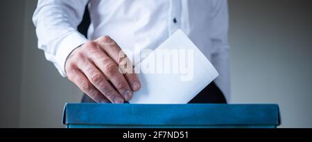 male hand putting vote in ballot Stock Photo