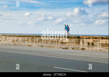 Two Cuban teenager boys walk atop the seawall along the Melecon in Havana, Cuba. Stock Photo