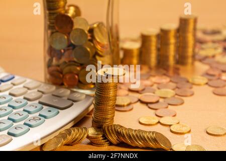 Pile of coins on a table with a lot of different coins around it and a calculator on a wooden table. Save money concept banner Stock Photo