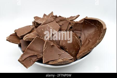 Broken chocolate Easter egg in a bowl isolated on white background Stock Photo