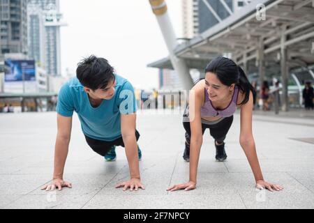Young asian couple athlete in sportswear exercising with push up on the floor in the city Stock Photo