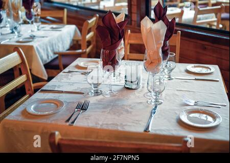 Rustic wooden dining table with tableware and glass in restaurant Stock Photo