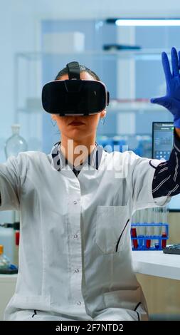 Professional scientist wearing virtual reality glasses using medical inovation in lab. Team of researchers working with equipment device, future, medicine, healthcare, professional, vision, simulator Stock Photo