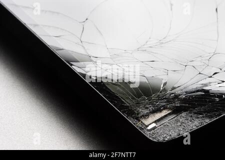 Closeup of a broken smartphone with cracked screen isolated on a gray background. Stock Photo