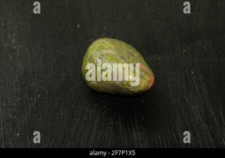 Unakite pebbles green epidote natural mineral stone from Republic of South Africa RSA on a black background. Mineralogy, geology, magic of stones, sem Stock Photo